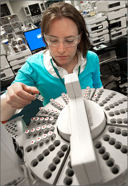 Photo of a female researcher examining oil samples as they are put into a gas chromatograph.