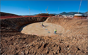 In a photo, two men in orange safety belts work inside a circular pit that formed the foundation for the 90-meter tower.