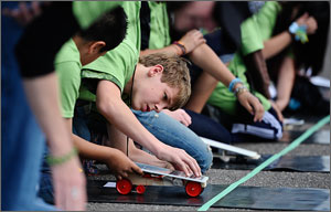 Photo of a row of students closely examining their solar model cars, before race start.