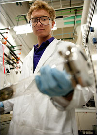 Photo of a man in a lab coat holding a glass tube.