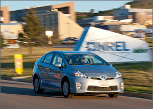 Photo of a man driving a plug-in hybrid vehicle outside of NREL.