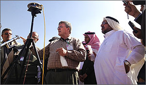 Photo of a group people standing around a solar monitoring instrument on a tripod.