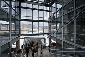 Photo of a group of people standing in the entry to a multi-level parking structure. The NREL campus is visible in the background. 