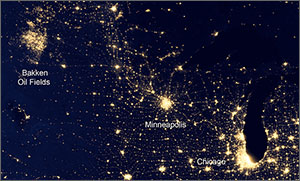 This is a satellite image in black and yellow – showing darkness and light. Concentrated lights appear around the Bakken Oil Fields and the cities of Minneapolis and Chicago.