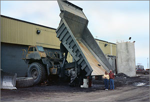 Photo of a man and woman standing near a large dump truck.