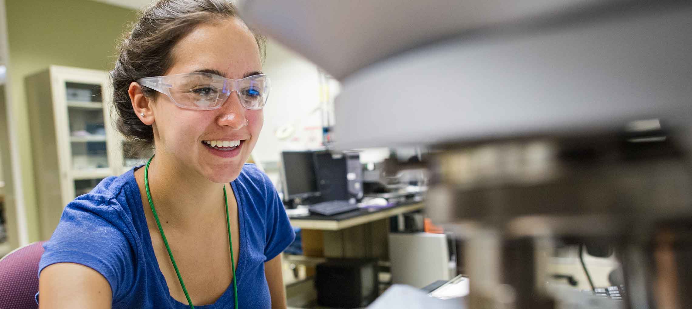 Photo of a woman using lab equipment to look at a silicon wafer.