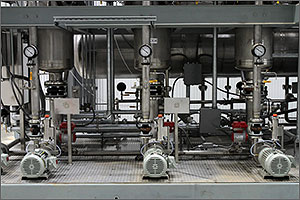 This is a photo of a biorefinery evaporator, composed of stainless-steel pipes, gauges, and pumps.