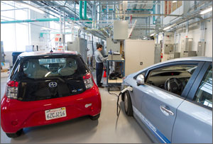 Photo of a researcher working in a laboratory with two electric vehicles and various power equipment.
