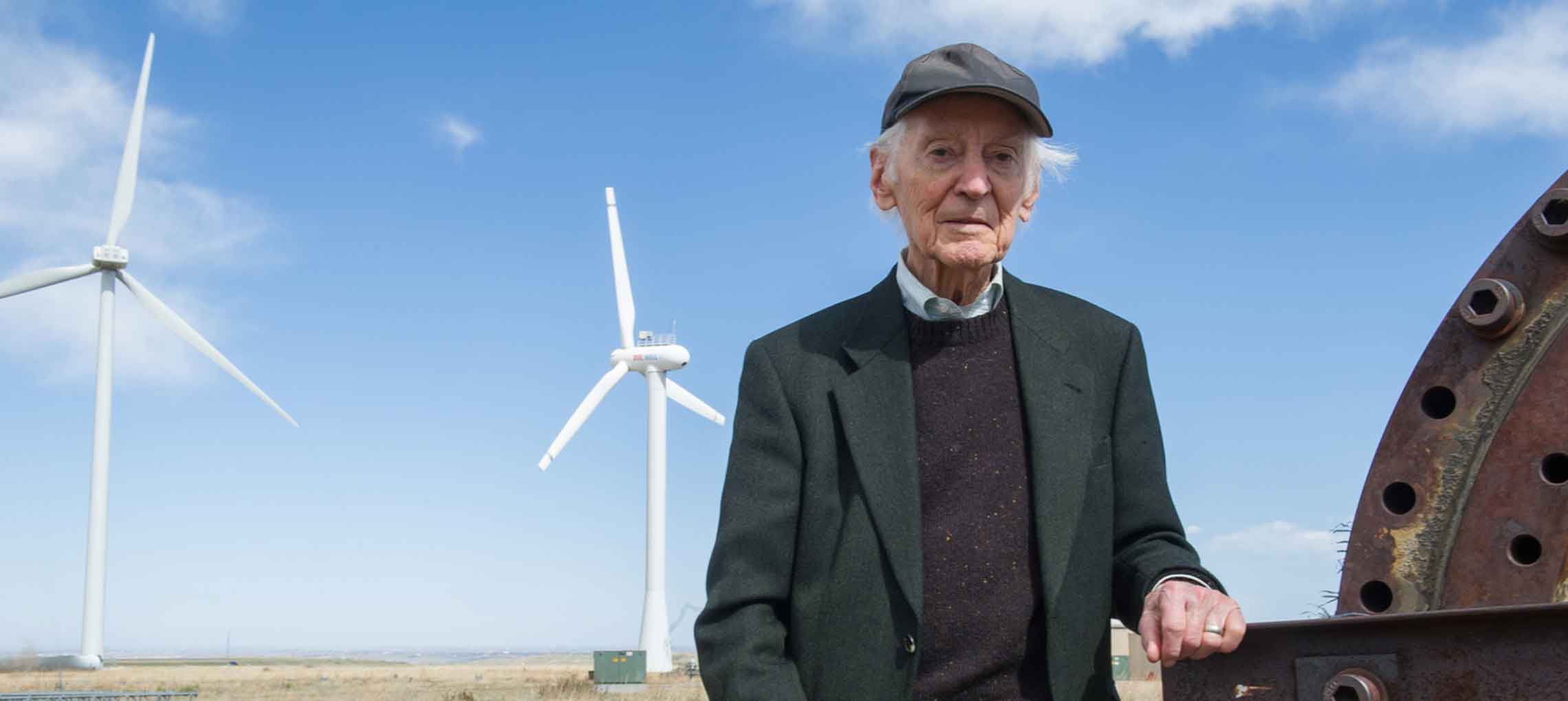 Photo of a man standing in front of megawatt-scale wind turbines.