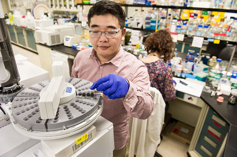 Researcher operates a mass spectrometer in an NREL laboratory.
