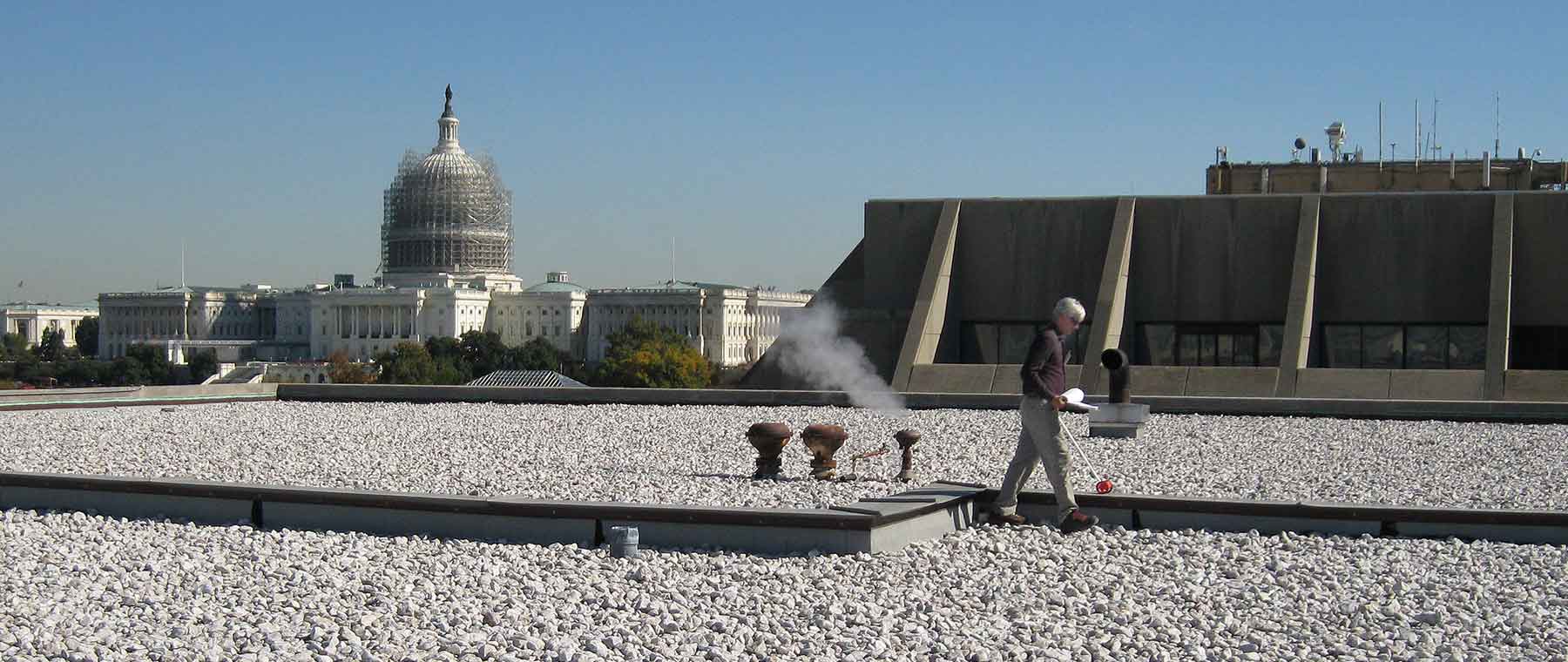 One man takes measurements atop a federal office building in Washington, D.C.