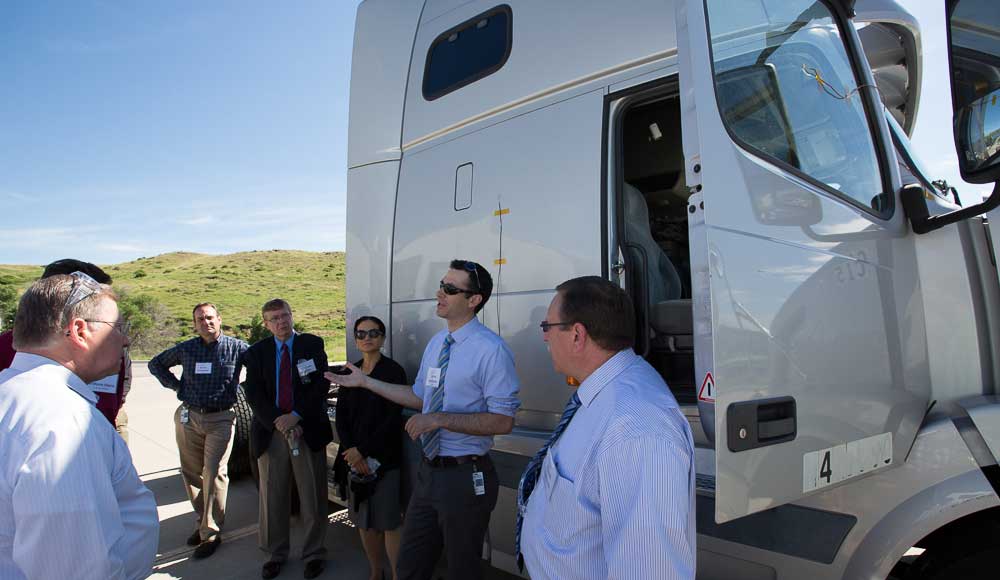 Photo of a group of people standing near a heavy-duty vehicle.