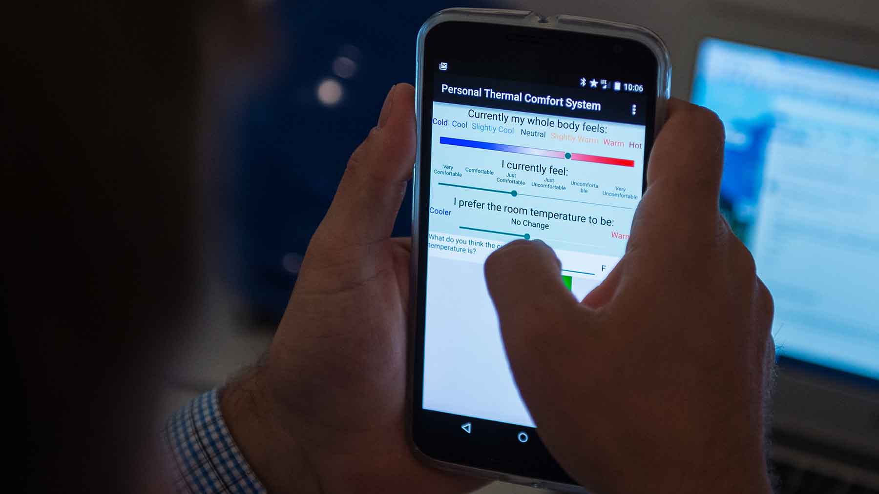 Photo shows a man using a smartphone app to register his comfort level.