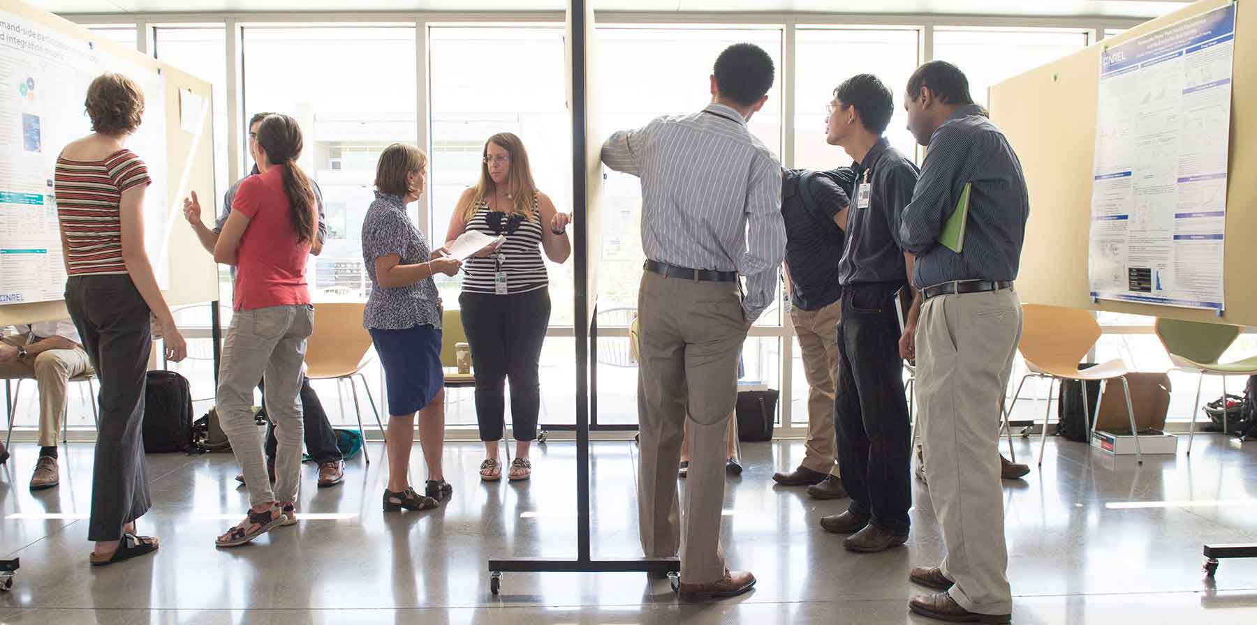 A group of people examine posters displaying results of LDRD-funded research.