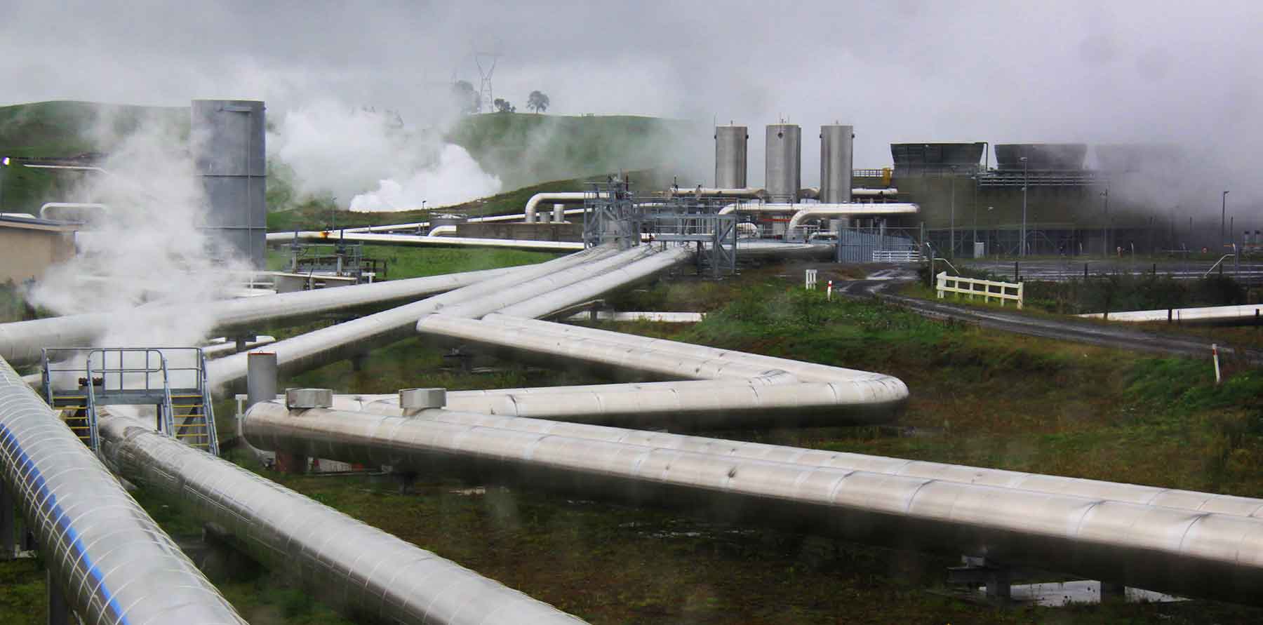 Photo shows a series of pipes emerging from a power station.