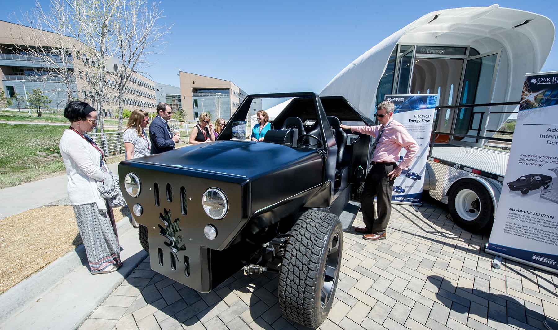 People stand next to a 3D-printed vehicle and house that were exhibited at the summit.