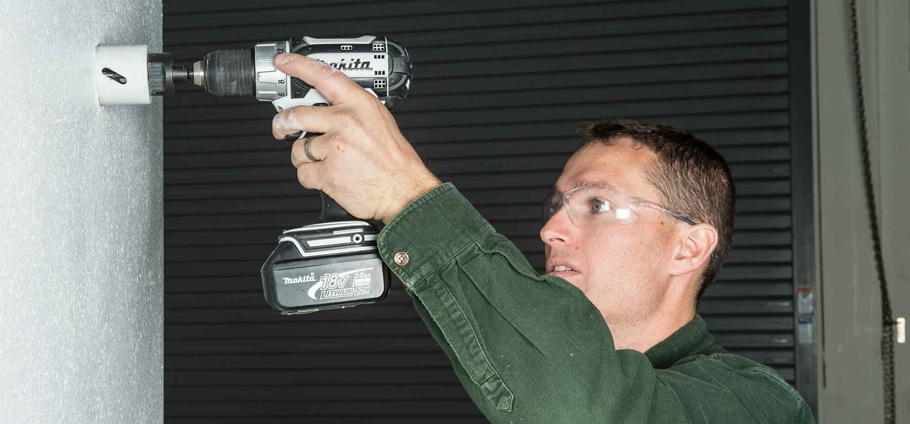 Photo of a man drilling into a wall.