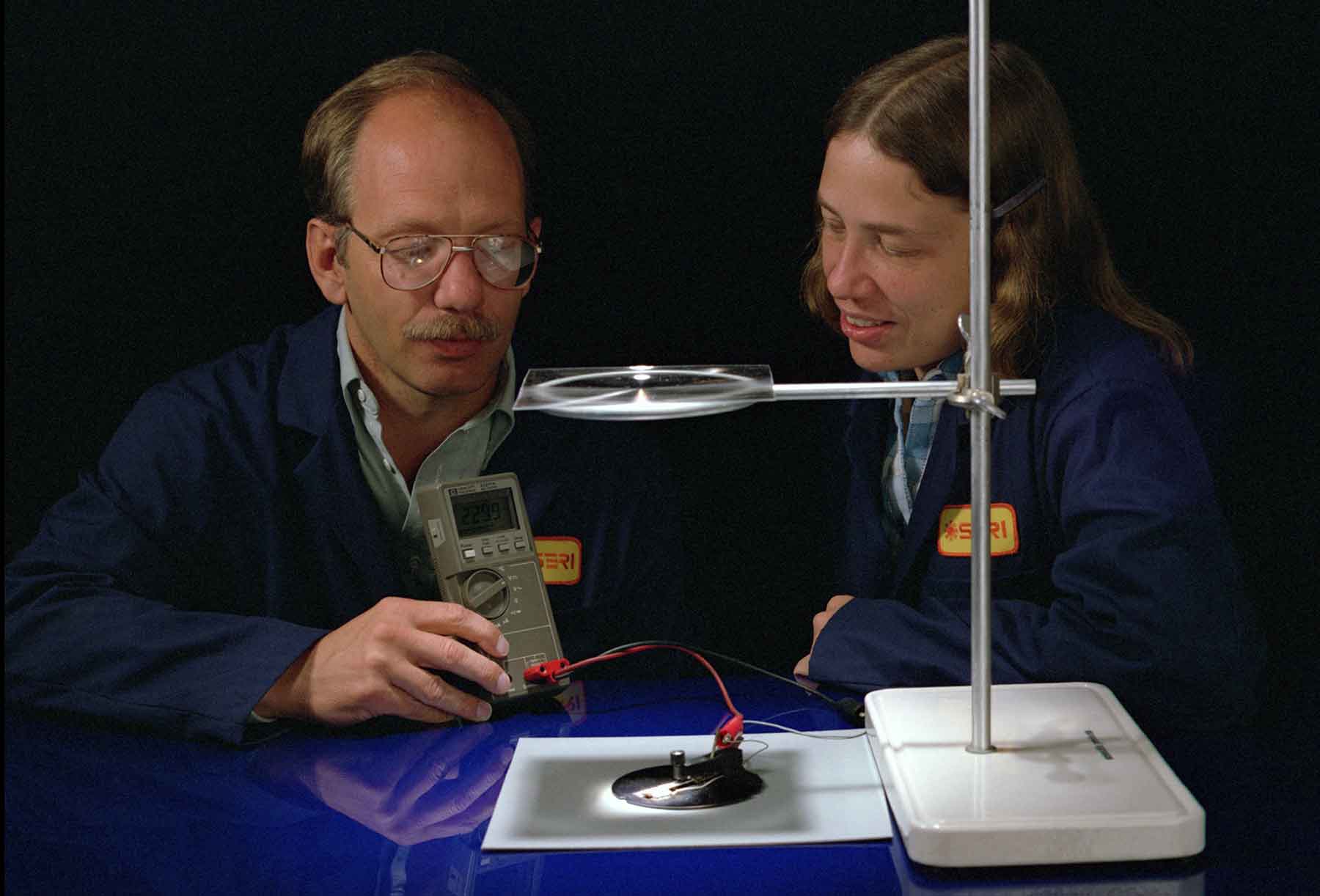 A man and a woman look at a solar cell.