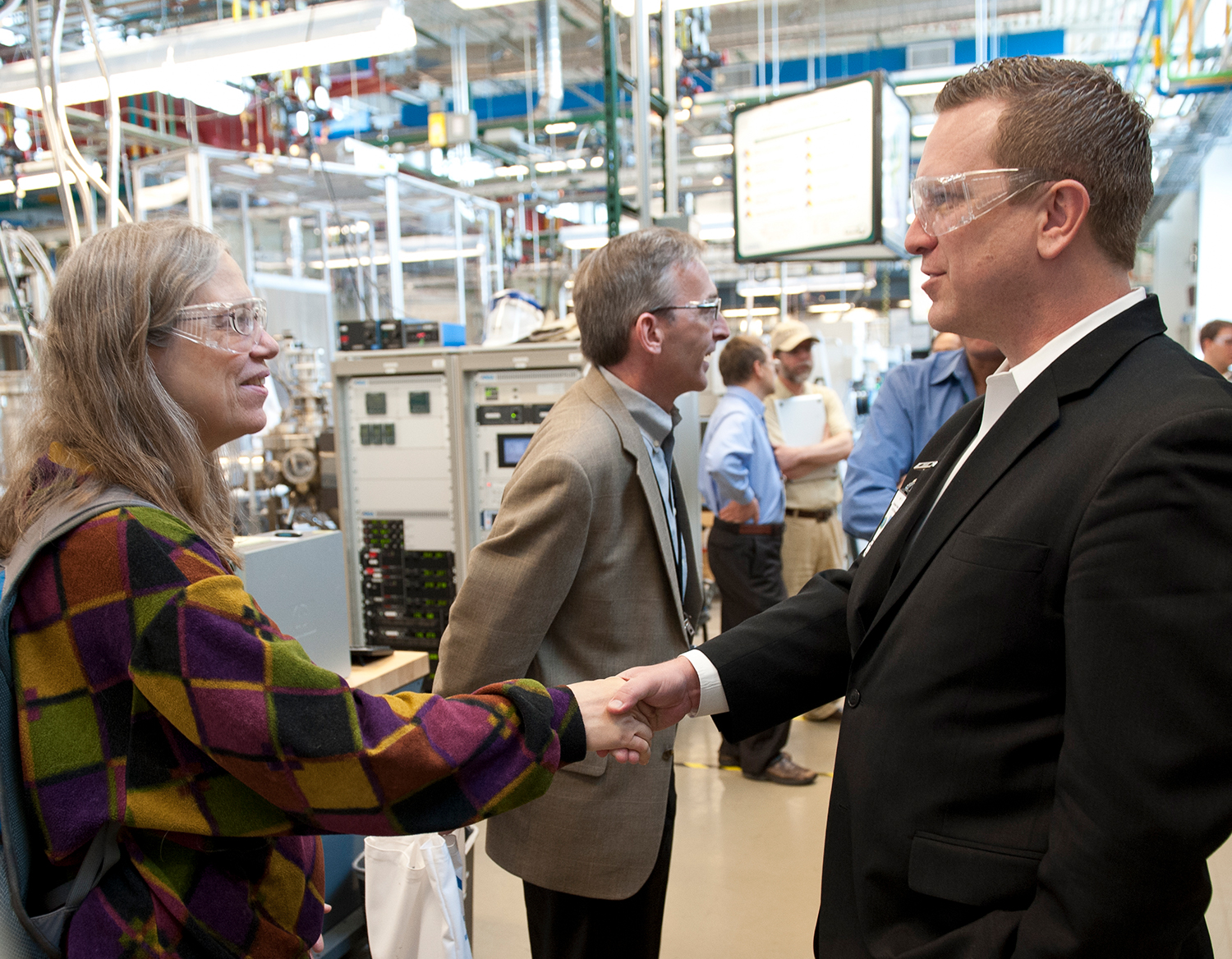 A woman talks to two men in a laboratory.