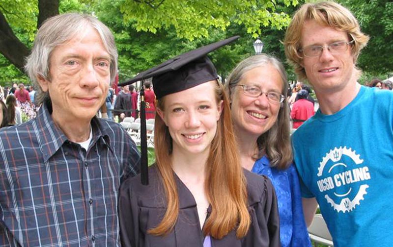 A man and a woman pose with a younger woman holding a diploma and a younger man.