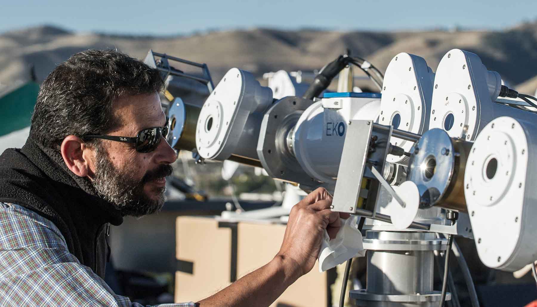 A man works with solar radiation instruments outdoors.