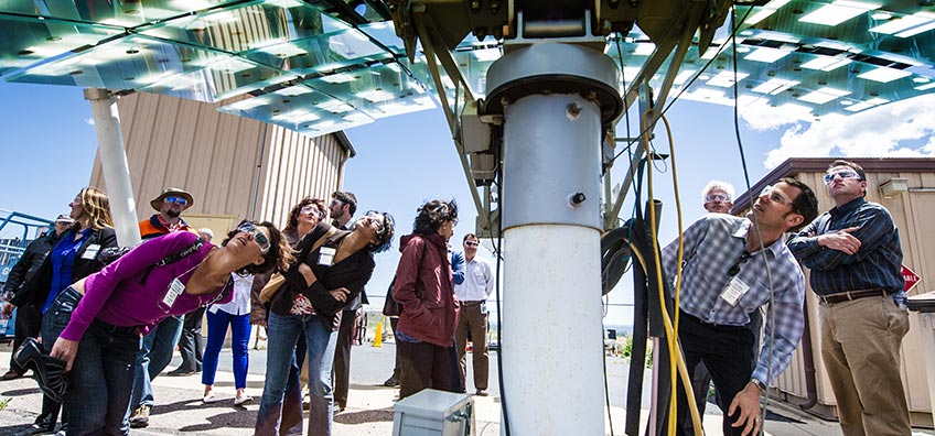 People look up at a piece of solar equipment.