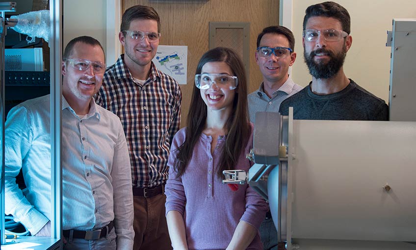 Four men and a woman stand inside a research laboratory at NREL.