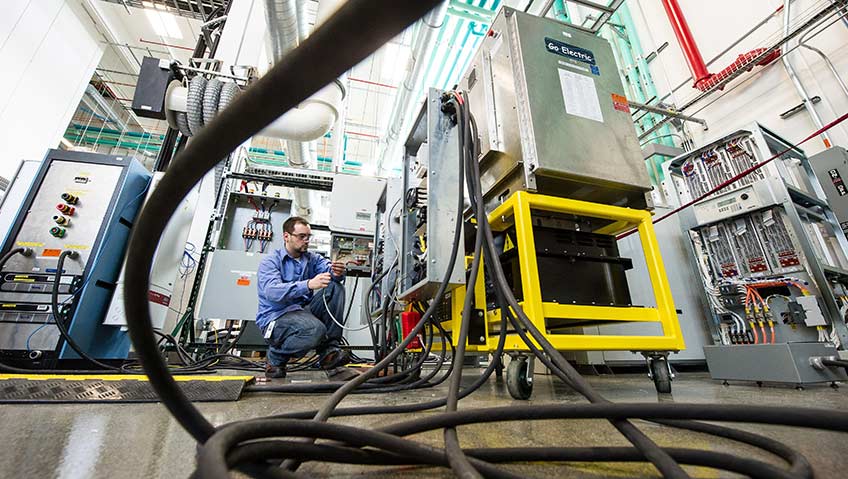 A man works on a large piece of equipment in an NREL lab.