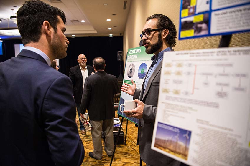 Two groups of men stand talking among posters.