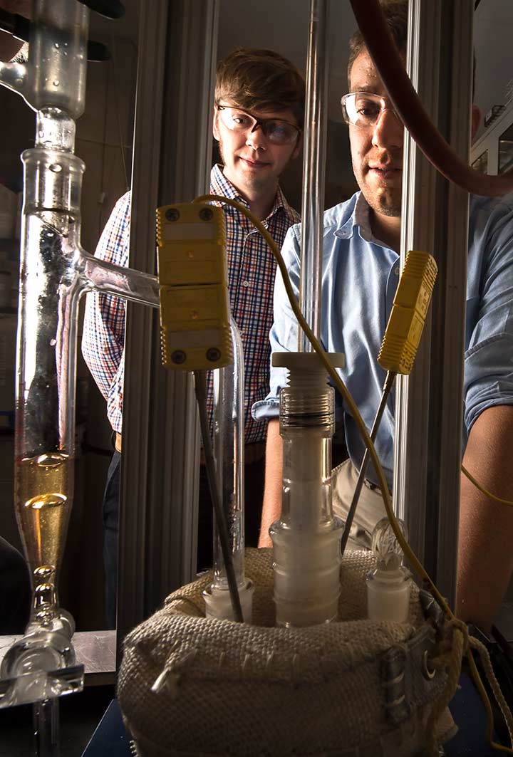 Two scientists look at glass flasks and tubes in a laboratory.