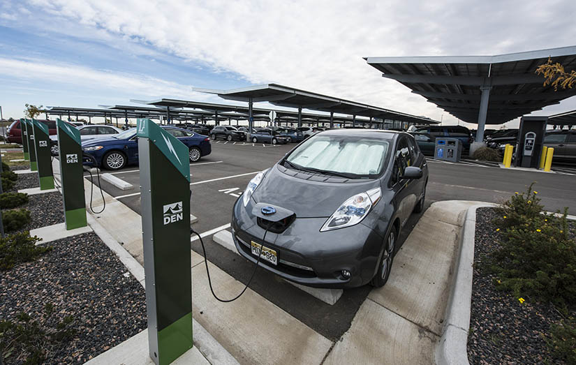 An electric vehicle is connected to a charger in a parking lot.