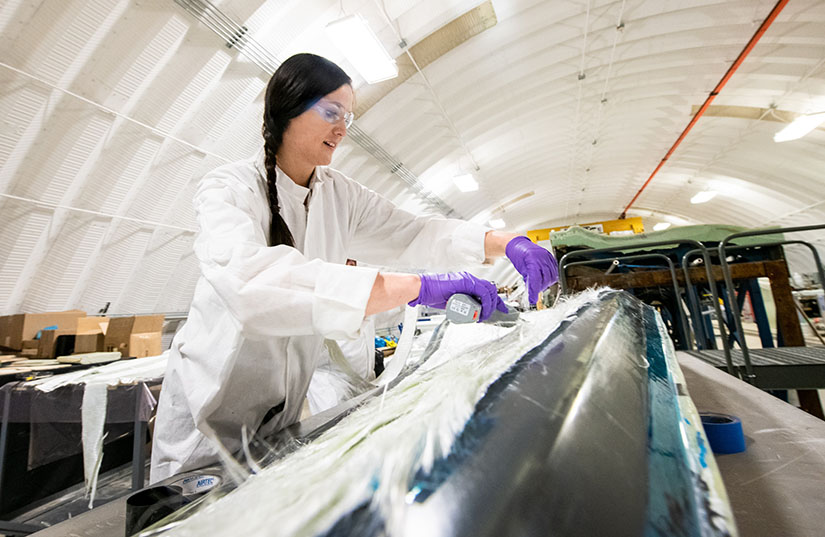 A woman works on the manufacture of a wind turbine blade.
