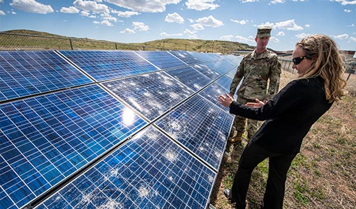 Photo of two people outside talking next to a solar panel array