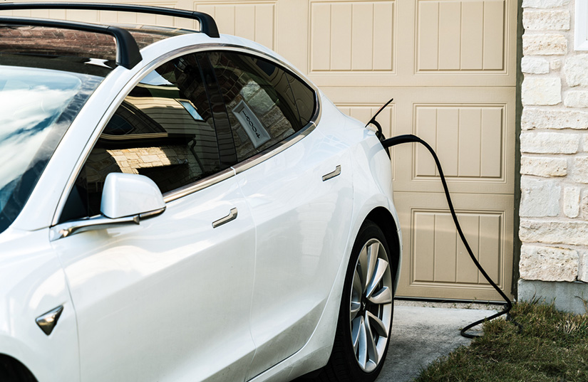 Photo shows an electric vehicle charging at a home.