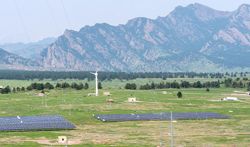 A field of solar panels with mountains in the background.