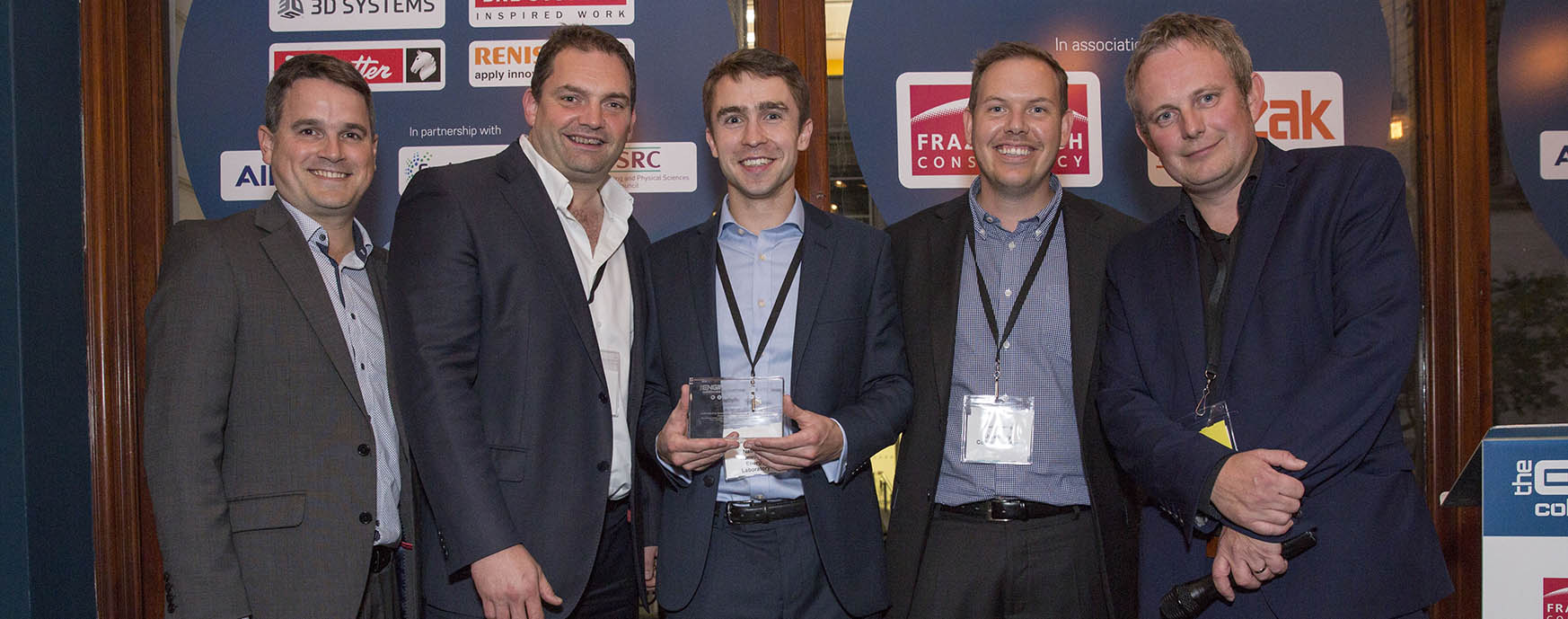 Photo of five men standing in front of an event display.