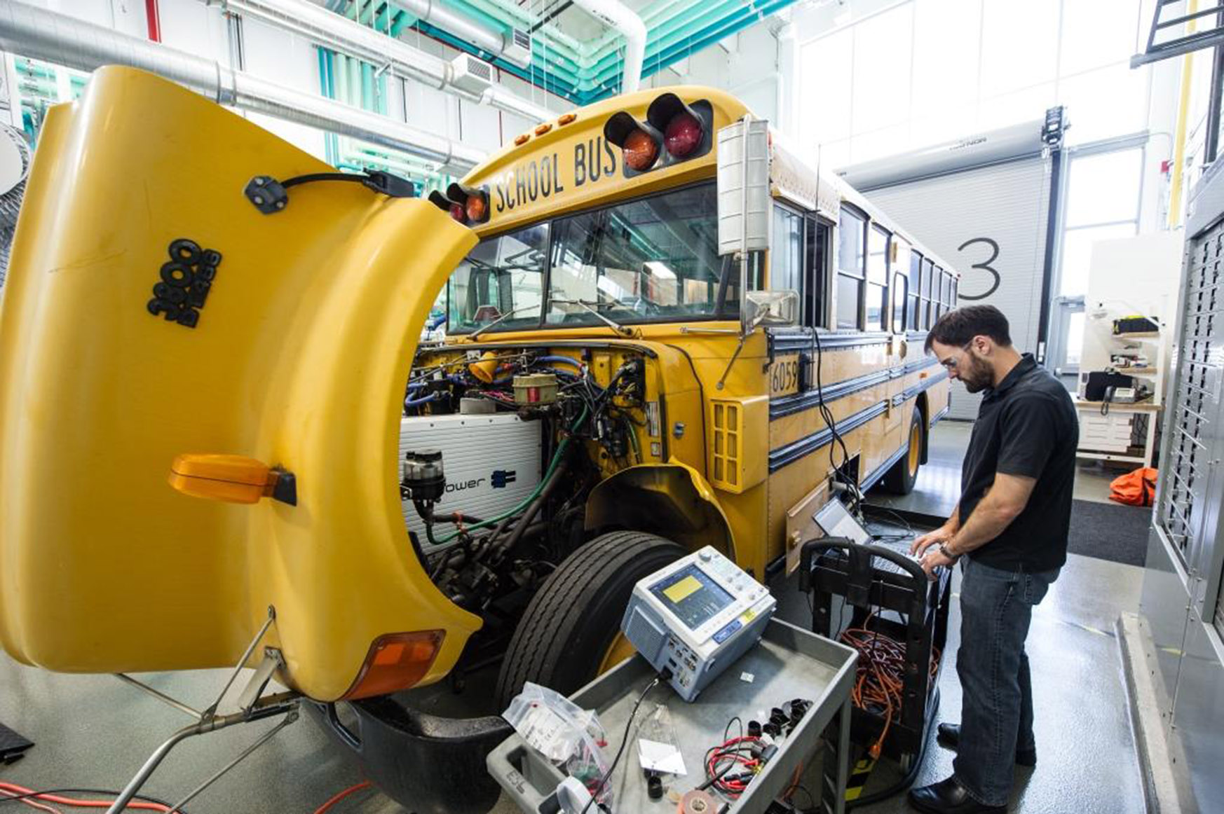 Photo of school bus connected to scientific equipment in laboratory setting.