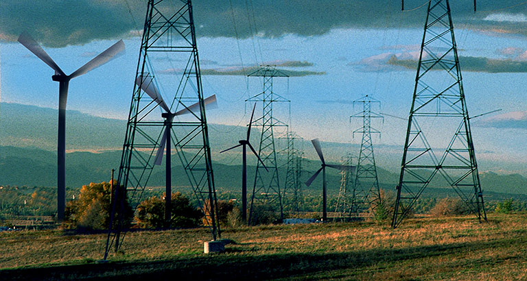Electricity towers and wind turbines against a cloudy sky and landscape