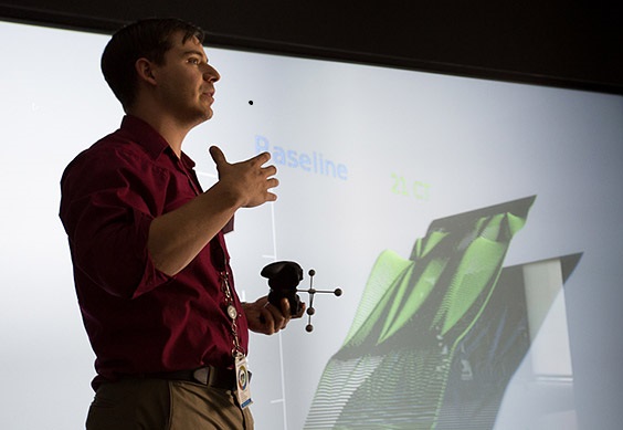 Photo of researcher standing next to abstract 3D image