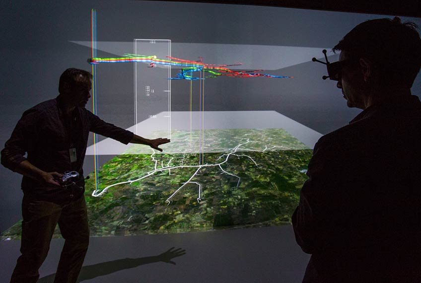 Two people looking at a 3D interactive graphical data the Visualization Center in the Energy Systems Integration Facility (ESIF).