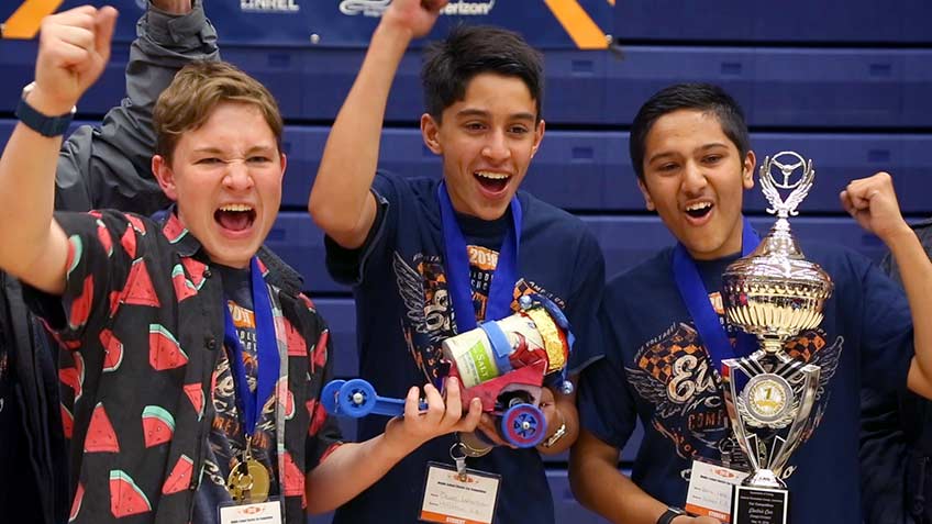 Three boys celebrating their victory at the middle school car competition.