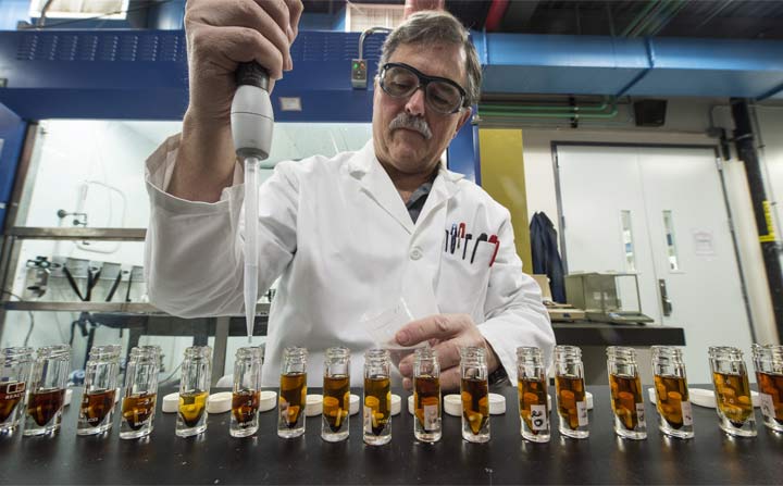 Man in lab coat taking bio-oil samples from test tubes.