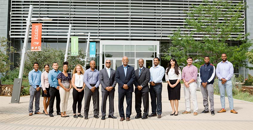 A group of scientific researchers stand outside the entrance to the Research Support Facility at the National Renewable Energy Laboratory.