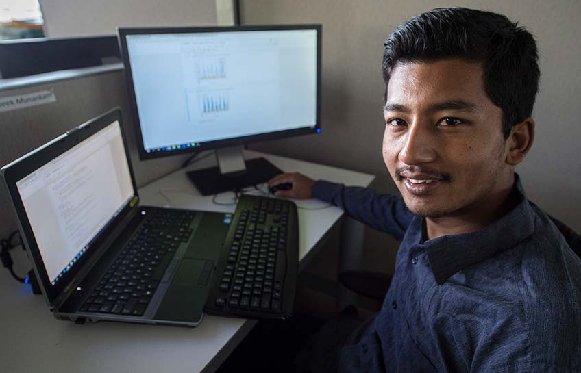 A man sits at a desk as he works on a computer