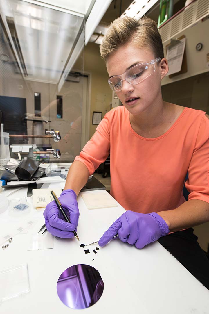 A woman looks at silicon samples on a counter with scientific instruments