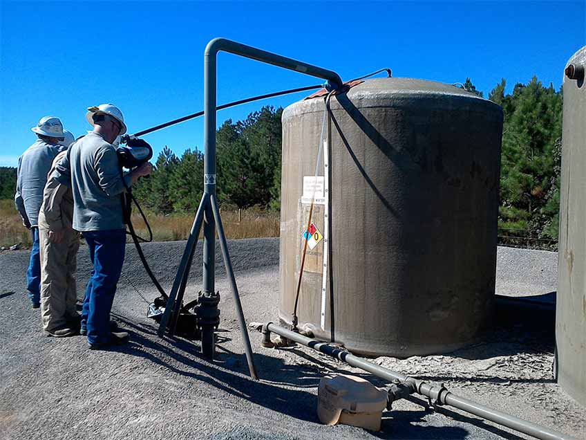 Photo of several researchers with their backs to the camera in the field measuring methane emissions.