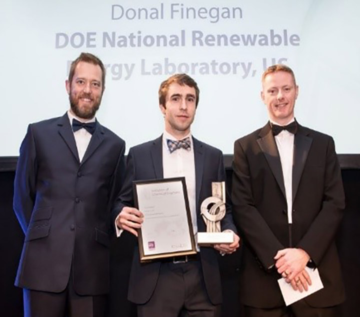 Photo of two men standing with Donal Final of the National Renewable Energy Laboratory, who is holding an award and plaque.