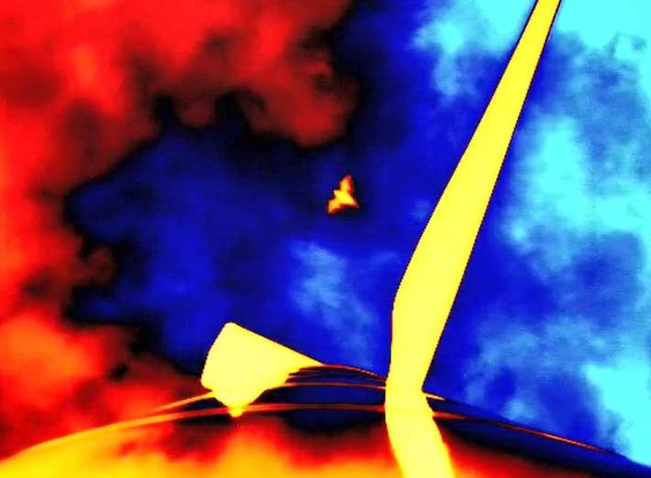 Thermal image looking up at the nacelle of a wind turbine. There is one blade pointing in the upper right of the image and a bat approaching in the center