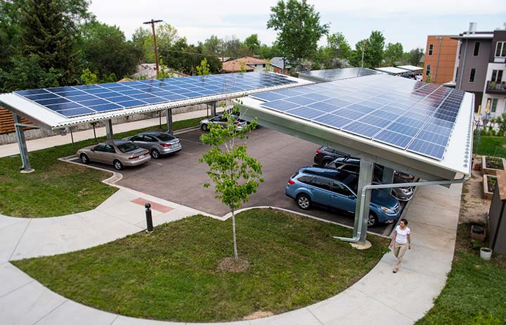Rooftop solar panels above full parking lot of vehicles.