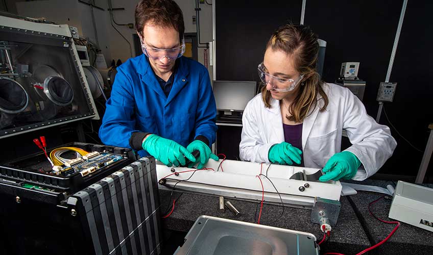 A man and woman set up a machine in a lab.